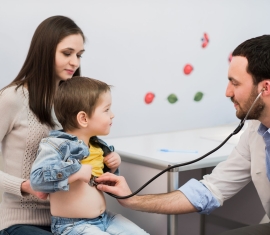 Pediatrician doctor examining kid boy. Mother holding baby.